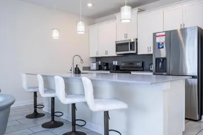 a kitchen with white cabinets and a counter with stools at Gorgeous 4 BR with pool and lake view in Kissimmee