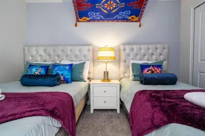 two beds in a bedroom with purple and blue pillows at Gorgeous 4 BR with pool and lake view in Kissimmee