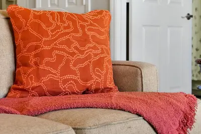 an orange pillow on a couch with a red blanket at Windsor Palms Home - Pool, Theatre &Near Disney in Kissimmee
