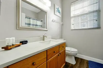 a bathroom with a sink and a toilet and a mirror at Windsor Palms Home - Pool, Theatre &Near Disney in Kissimmee