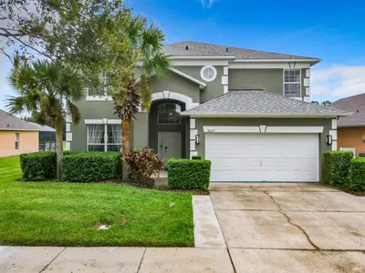 a house with a garage and a palm tree at 7BR Villa in Emerald Island w/ Resort Perks in Kissimmee
