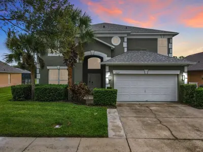 a house with a garage and a palm tree at 7BR Villa in Emerald Island w/ Resort Perks in Kissimmee