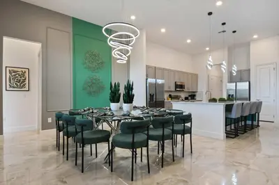 a dining room with a table and chairs and a kitchen at Luxurious 15BR Villa with Lake View & Game/Theater in Orlando
