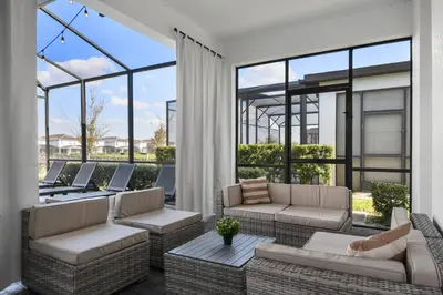a patio with couches and tables and windows at Epic Family Getaway: Themed Villa Near Disney ! in Kissimmee