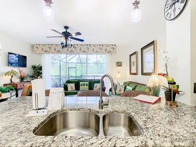 a kitchen with a sink and a living room at Adventureland Oasis - Resort Near Disney in Kissimmee