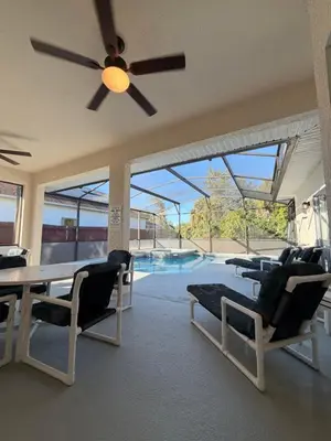 a living room with a table and chairs and a pool at Fun Disney Oasis Pool House with Spa Game Room Kids Playground and 10 min from Disney in Kissimmee