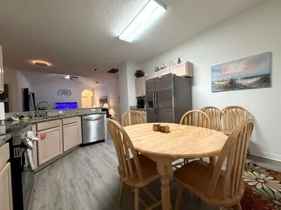 a kitchen with a wooden table and chairs in a kitchen at Fun Disney Oasis Pool House with Spa Game Room Kids Playground and 10 min from Disney in Kissimmee