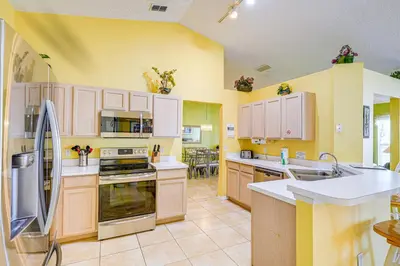 a large kitchen with yellow walls and white cabinets at 9 Mi to Walt Disney World Family Home with Pool! in Orlando