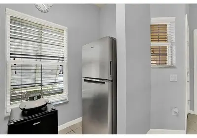 a kitchen with a stainless steel refrigerator next to a window at 3157 YL - Encantada Serenity Retreat Elegant Villa Close to Disney in Kissimmee