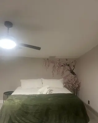 a white bedroom with a bed with a green blanket at The Secret Garden Games Getaway in Orlando