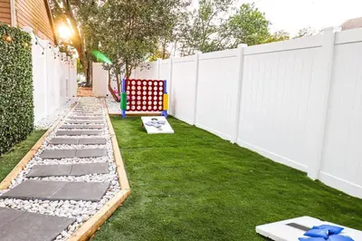 a small backyard with a white fence and a lawn at FunTropicalTinyGemUCF in Orlando