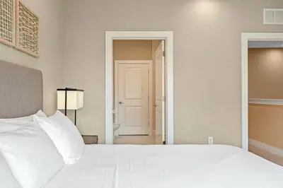 a bedroom with a white bed and a door to a hallway at Casa 4Q Elegante Perto da Disney – Magic Village in Orlando