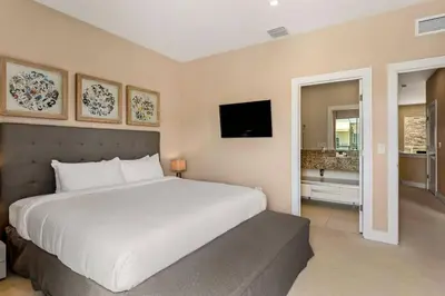 a bedroom with a large white bed and a television at 7639- Encantadora Casa com 3 Suítes no Magic Village Yards, Perto da Disney e da Rota 192 in Orlando