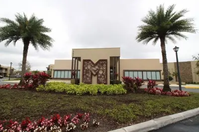 a building with palm trees and flowers in front of it at 7639- Encantadora Casa com 3 Suítes no Magic Village Yards, Perto da Disney e da Rota 192 in Orlando