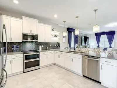 a large kitchen with white cabinets and appliances at Magical Mansion - 15 Min to Disney - Storey Lake in Kissimmee