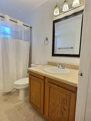 a bathroom with a sink and a toilet and a mirror at Apartamento 3 Quartos a Minutos da Disney in Kissimmee