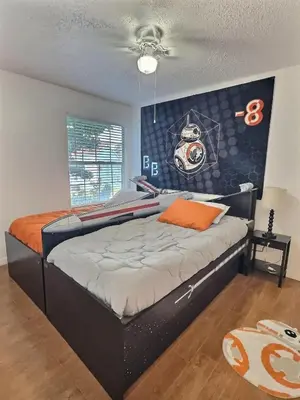 a bedroom with a black bed with an orange pillow at Apartamento 3 Quartos a Minutos da Disney in Kissimmee