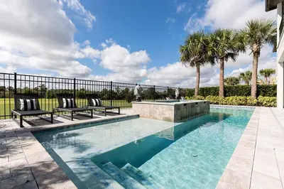 a swimming pool with two chairs and palm trees at The Nicklaus View Haven-TB007 in Orlando