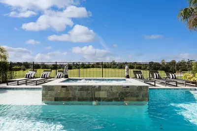 a pool with chairs and a rainbow in the sky at The Nicklaus View Haven-TB007 in Orlando
