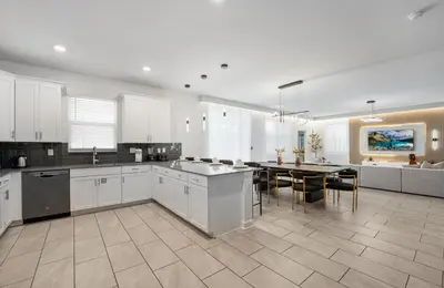 a large kitchen with white cabinets and a table at 2858 Storey Lake brand new 19guests pool game room in Kissimmee