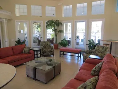 a living room with red couches and tables and windows at Celtic Palms: Private Pool & Near Disney Magic in Kissimmee