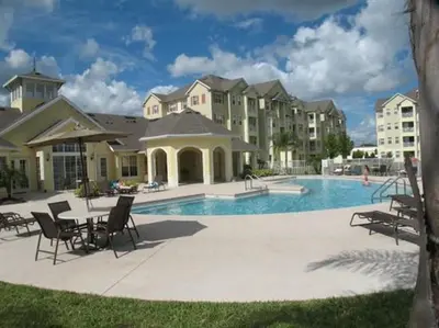 a pool with chairs and a table and some buildings at Cane Island Resort 2BR Condo, Close to Attractions in Kissimmee