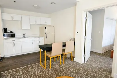 a kitchen with white cabinets and a black table and chairs at Montreal Suites Orlando in Orlando