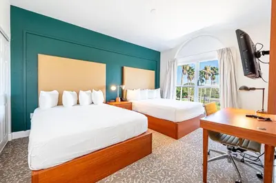 a hotel room with two beds and a desk and a computer at Montreal Suites Orlando in Orlando