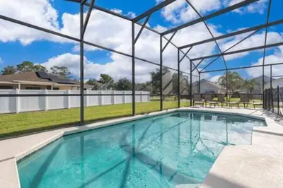 a large swimming pool with a large glass wall at Ruby Reds Escape in Kissimmee