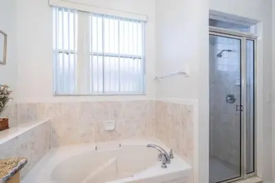 a white bathroom with a tub and a shower at Ruby Reds Escape in Kissimmee