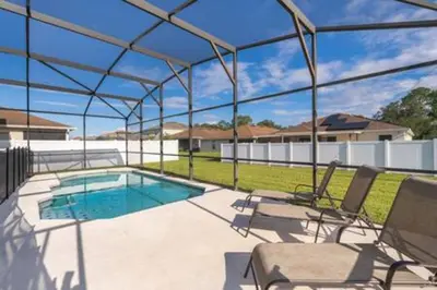 a swimming pool with two chairs and a swimming poolvisor at Ruby Reds Escape in Kissimmee