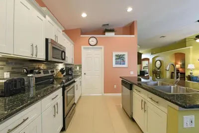 a kitchen with white cabinets and a clock on the wall at Caribbean Breeze: Pool Home 3 Miles to Disney in Kissimmee