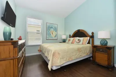 a bedroom with a bed and a dresser and a television at Caribbean Breeze: Pool Home 3 Miles to Disney in Kissimmee