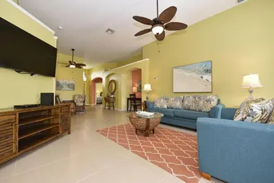 a living room with a blue couch and a flat screen tv at Caribbean Breeze: Pool Home 3 Miles to Disney in Kissimmee