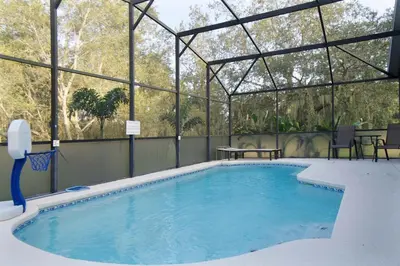 a large swimming pool with a tent and a table at Four Seasons Vacation, heated Pool, 3mile 2 Disney in Kissimmee