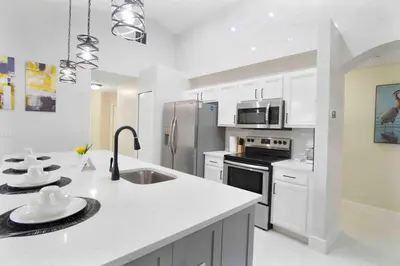 a kitchen with white cabinets and a stainless steel refrigerator at Four Seasons Vacation, heated Pool, 3mile 2 Disney in Kissimmee