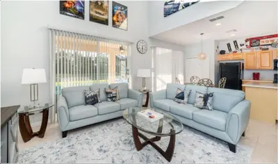 a living room with two blue couches and a table at Emerald Island Getaway – Sleeps 13! in Kissimmee
