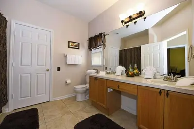 a bathroom with a sink and a toilet and a mirror at Family Villa Near Disney with Private Pool in Kissimmee