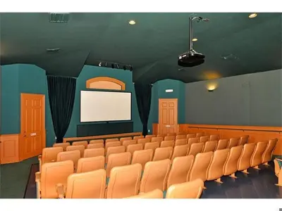 an auditorium with orange chairs and a white screen at Family Villa Near Disney with Private Pool in Kissimmee