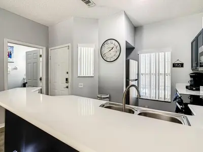 a kitchen with a sink and a clock on the wall at Hogwarts Escape: Magical Retreat Near Disney in Kissimmee