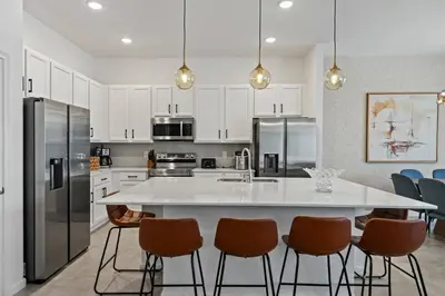 a kitchen with a large white island with bar chairs at Paradiso Grande Resort 9Bedroom Vacation Home 6210 in Orlando