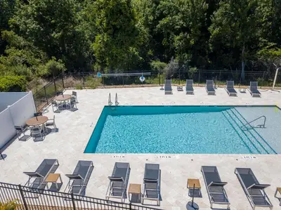 an empty swimming pool with chairs and a table and a volleyquet at Prime Location 4BD Townhome with pool and Grill in Kissimmee