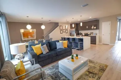 a living room with a blue couch and a kitchen at Prime Location 4BD Townhome with pool and Grill in Kissimmee
