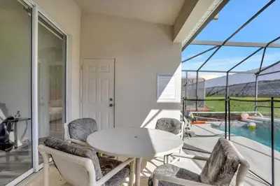 a room with a table and chairs and a pool at Luxury Pool Home 3 Miles from Disney & More! in Kissimmee