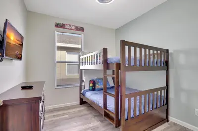 a room with two bunk beds and a desk at Luxury Pool Home 3 Miles from Disney & More! in Kissimmee