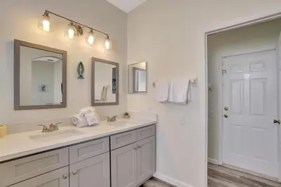 a bathroom with two sinks and two mirrors at Luxury Pool Home 3 Miles from Disney & More! in Kissimmee