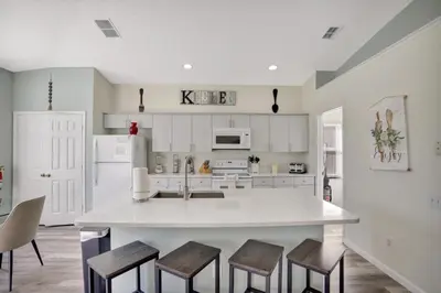 a kitchen with a large white island with stools at Luxury Pool Home 3 Miles from Disney & More! in Kissimmee