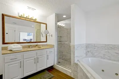 a bathroom with a tub and a sink and a mirror at 12538 INTERNATIONAL DRIVE #C303 ORLANDO 2BED in Orlando