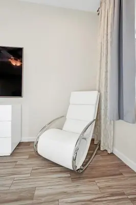 a white chair in a corner of a room at LAKE VILLA 6bd, all un-suite, pool, spa, grill in Kissimmee