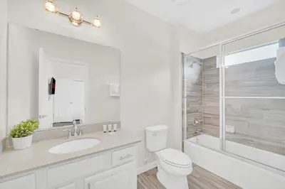 a bathroom with a toilet and a sink and a shower at LAKE VILLA 6bd, all un-suite, pool, spa, grill in Kissimmee